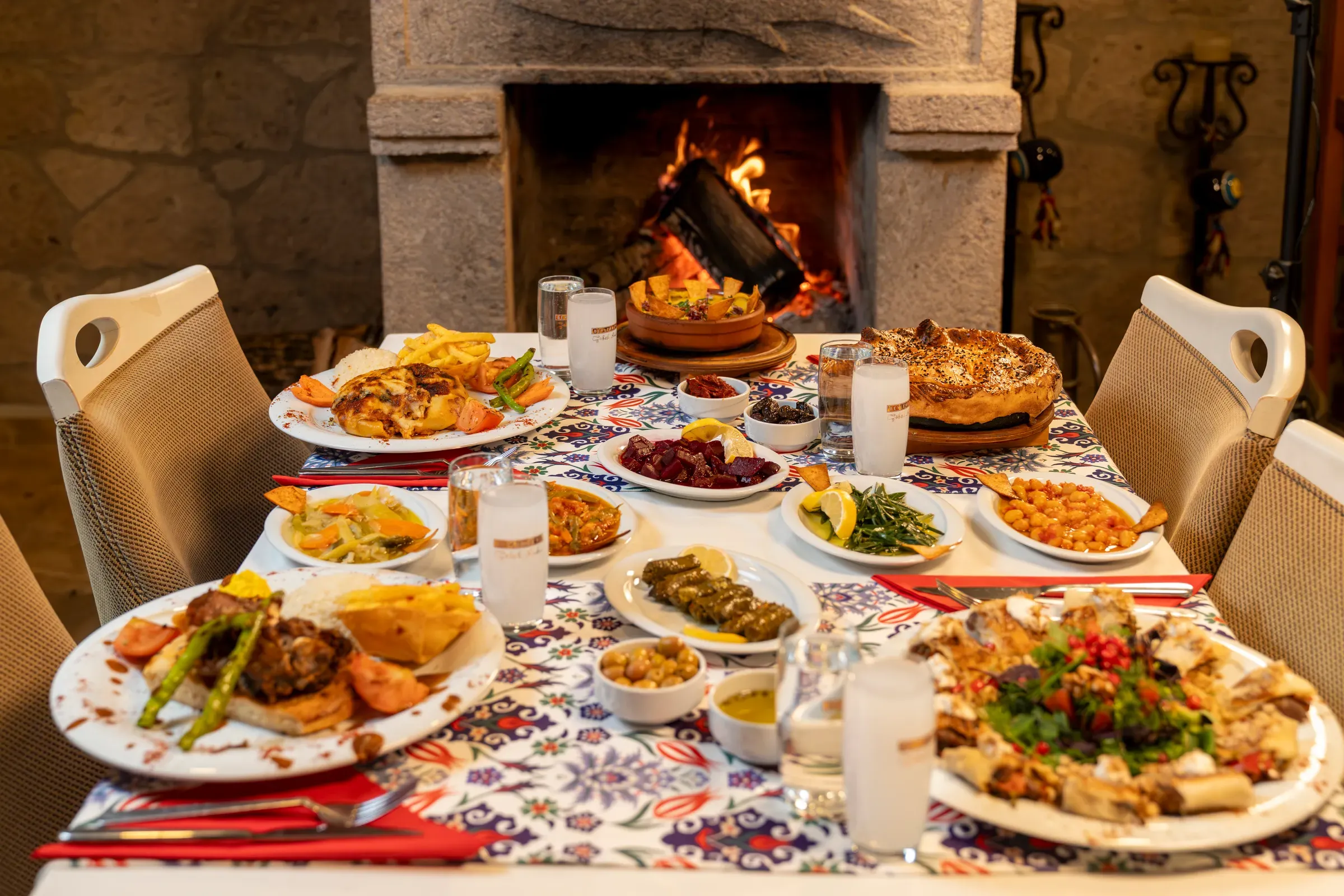 Dinner table with meze and mains in front of the fireplace