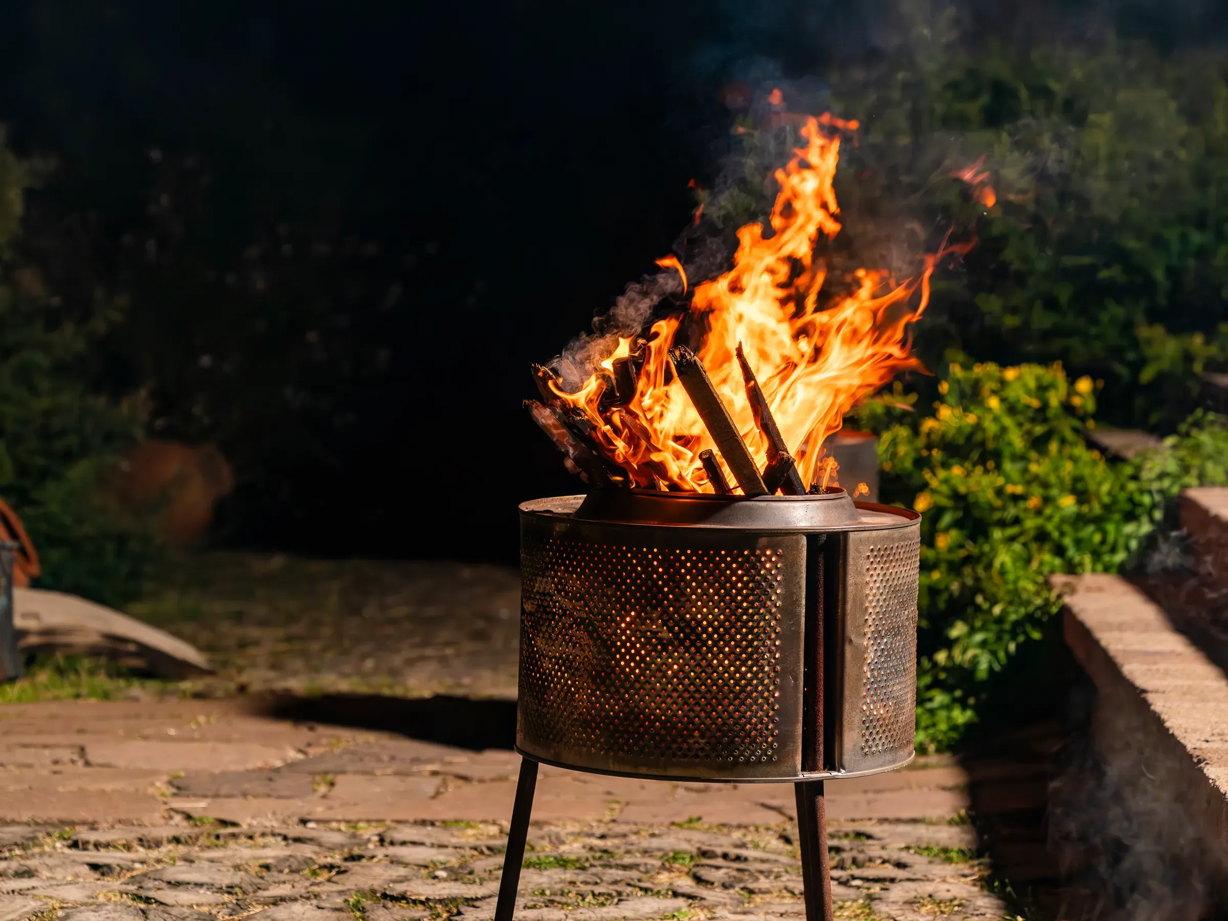 A fire basket burning in the stone courtyard at night