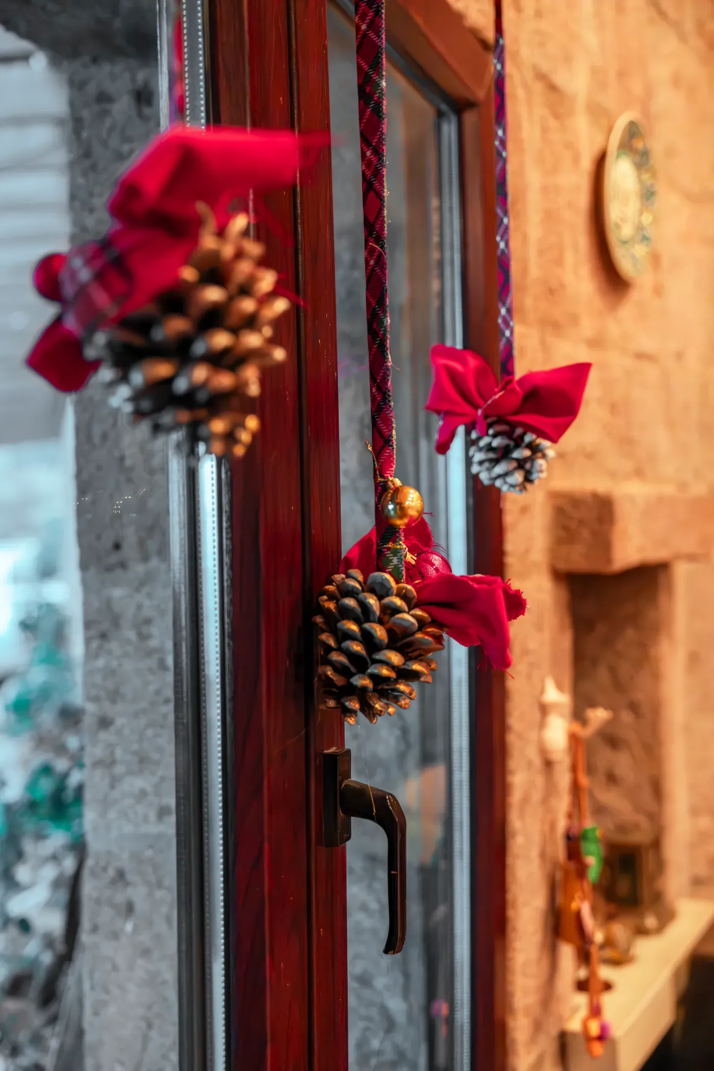 Pine cone ornaments with red ribbons on the window